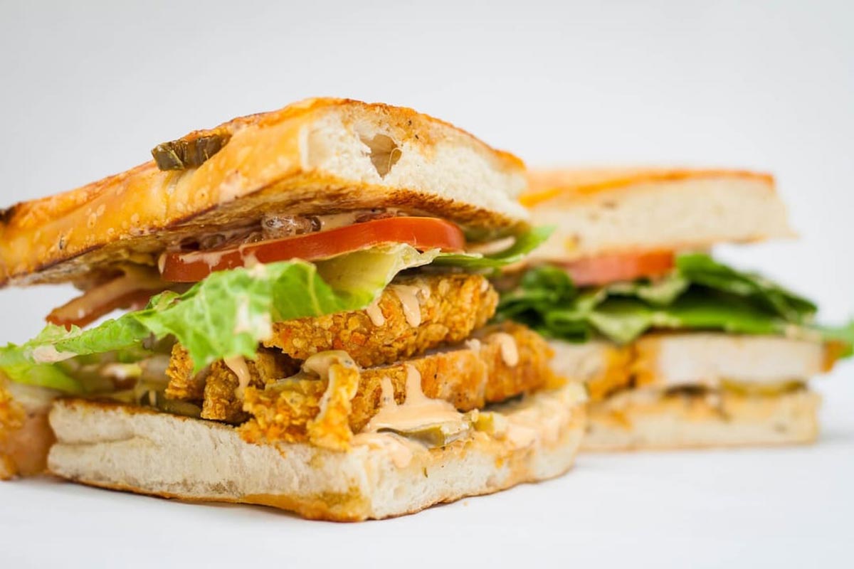 A close-up of a Full Belly Deli sandwich with fried chicken.
