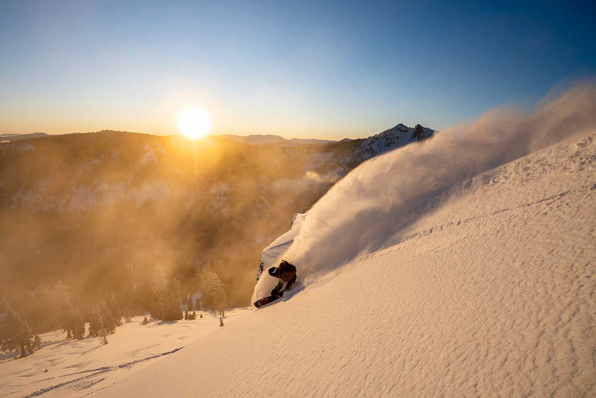A snowboarder in the Tahoe Basin backlit by golden light.